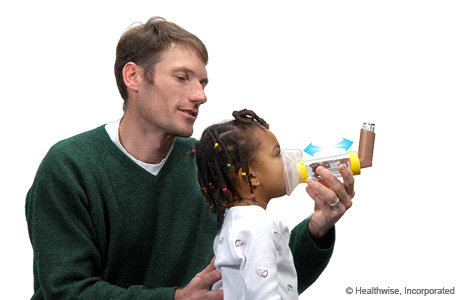 A child breathing in the medicine using the mask spacer